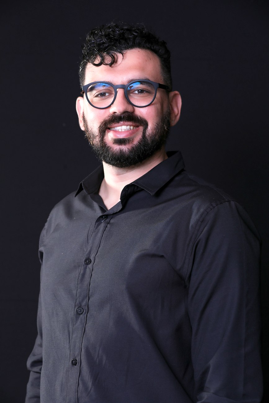 Retrato de Felipe Queiroz, psicólogo, em fundo escuro.